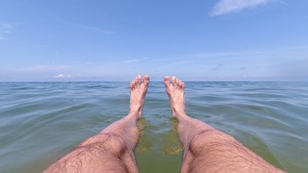 Man Floating On Sea Water With Legs Stretched Out On Sunny Day
