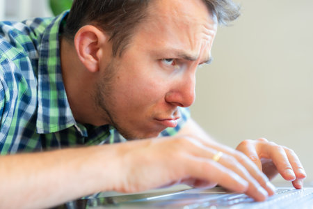 Frustrated Man Leaning Forward Staring At Laptop Screen While Working From Homeの写真素材
