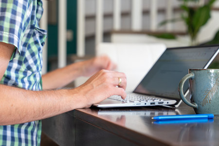 Person Typing On Laptop Indoors With Coffee Mug On Desk For Work From Home Productivityの写真素材