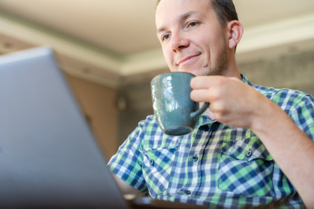 Man With Laptop And Coffee During Remote Work At Home, Freelancer Online In Casual Morning Routine, Productivityの写真素材