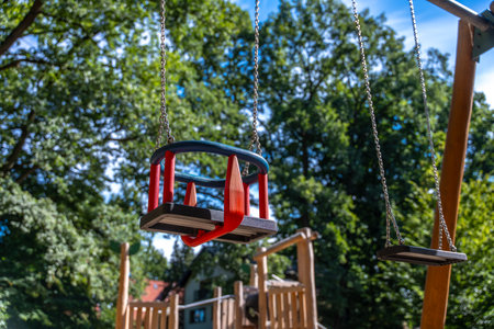 Toddler And Standard Swings Hanging At Park Playground, Sunny Outdoor Recreation For Familiesの写真素材