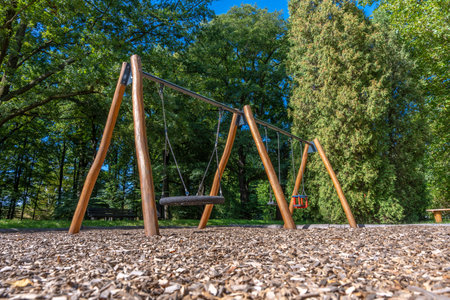 Wooden Swing Swingset In Outdoor Park, Empty Playground Amid Nature On A Summer Day For Recreationの写真素材
