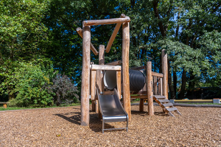 Wooden Playground Slide With Stairs And Tunnel Surrounded By Treesの写真素材