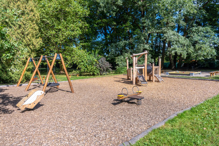 Empty Wooden Playground With Swings And Slide Surrounded By Treesの写真素材