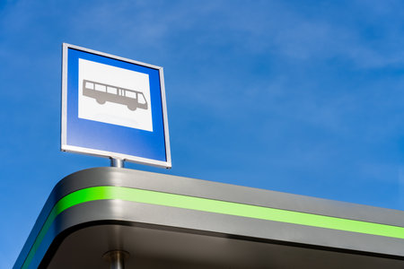 Blue Bus Stop Sign On Modern Shelter Roof Against Clear Sky, Public Transport Icon For Urban Commuter Information. Large Copy Spaceの写真素材