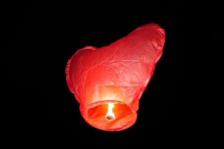 Red Heart Sky Lantern With Burning Flame At Night Isolated On Black, Romantic Celebration Holiday Symbolの写真素材
