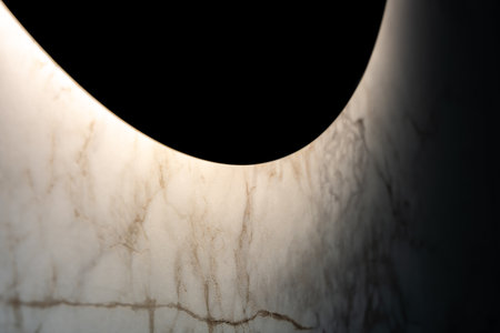 Round Bathroom Mirror With Soft Light Illuminating Marble Wall Surface With Elegant Texture And Modern Interior Ambienceの写真素材