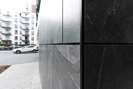 Dark Stone Exterior Panels With Natural Texture On Modern Building Facade And Urban Surroundingsの写真素材