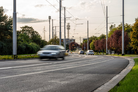 Urban Road With Cars Trees And Overhead Tram Wires During Evening Traffic In Modern City Infrastructureの写真素材