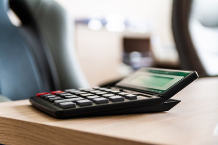 Black Calculator On Wooden Office Desk In Modern Workplace Settingの写真素材