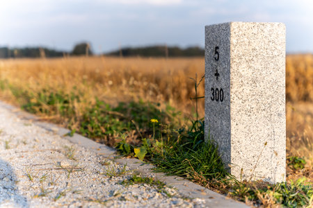 Granite Milestone Beside Rural Road In Autumn Landscape For Navigation And Infrastructure Themesの写真素材