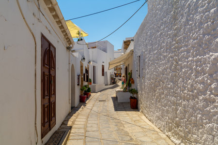 Sunny Whitewashed Tight Alley With Traditional Architecture And Stone Pathway In Mediterranean Village. Greece Travel Sceneの写真素材