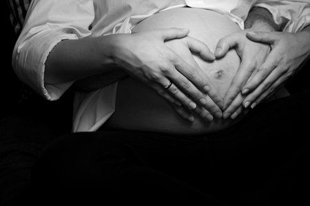 Pregnancy Belly With Couple Hands Heart Symbol Showing Love Maternity Expecting Family Parents. Intimate Black And White Maternity Photoshootの写真素材