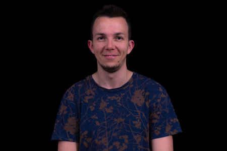 Friendly Man Portrait With Smile In Blue Patterned Tshirt On Black Background Headshot