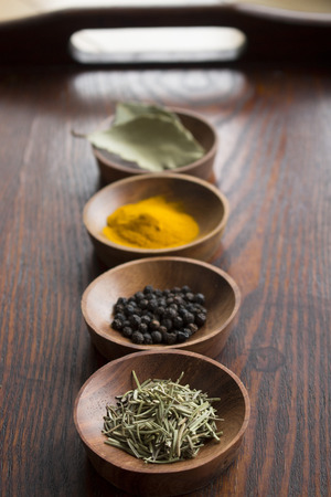 Dry herb served in wooden plate rosemary bay leaf black pepper turmericの写真素材