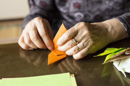 Hands of senior lady folding Origami paperの写真素材