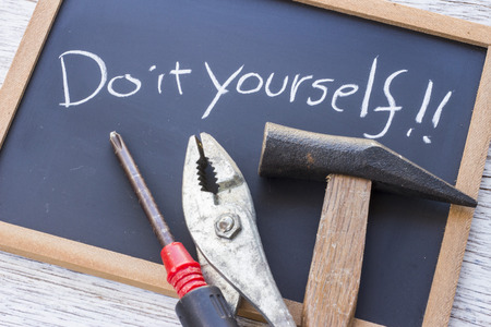 "Do it yourself" written on a blackboard and a hammer, a pliers and a screwdriverの写真素材