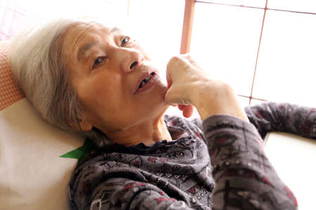 Senior Lady lying On The Nursing Bed With Serious Faceの写真素材