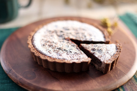 Whole chocolate tarts sliced on a circular wooden cutting boardの写真素材
