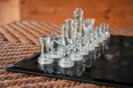 Glass chess set on a black marble board placed on a rattan tableの写真素材