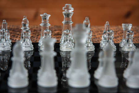 Glass chess set on a black marble boardの写真素材