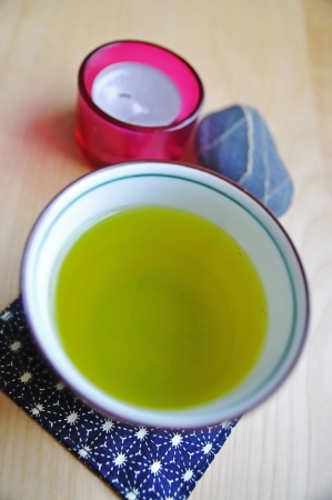 A fresh cup of green tea on table with candle and stoneの写真素材