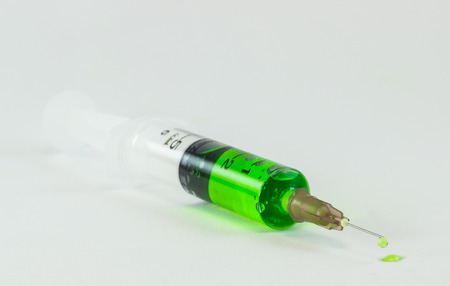plastic medical syringes containing multicolor solutions in medicine glass with white backgroundの写真素材