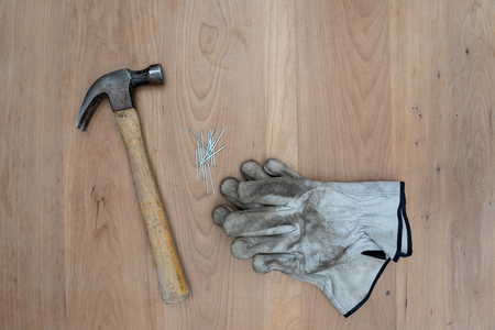 Tools that can be used by a carpenter are displayed on a woorden taebel. These can be a hamer, measuring tape, protective gloves and a sawの写真素材