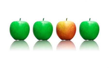 Four apples in a row , three being green and one is red wich makes it stand out as a sign of being differentの写真素材