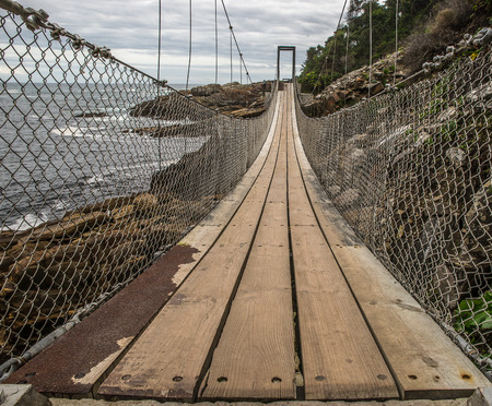 An unstable and dangerous looking bridge for pedestrians. This is often used to cross small rivers. The bridge consists of wooden planks and is suspended on rope of rope. You have to dare to do this if you want to come across the street.の写真素材