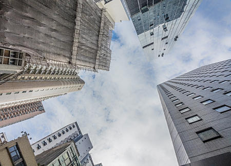 HONG KONG / CHINA-AUGUST 4 2017: Looking up to the sky in Hong Kong. The tall buildings can not be avoided and can be seen everywhere. Looking up straight up creates an abstract picture of the often glass office buildings.の写真素材