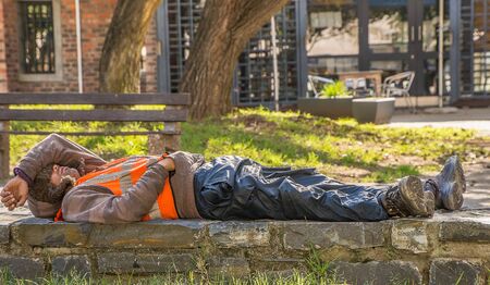 JOHANNESBURG / SOUTH AFRICA-AUGUST 11 2019: A black man worker is resting on a low brick wall. He...