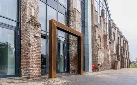 Dark brick facade of an old abandoned factory. The stones are damaged and outdated, but new windows...