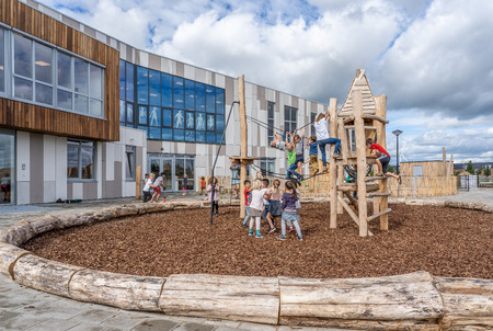 NIJMEGEN / NETHERLANDS-SEPTEMBER 13, 2019: Modern school building for children up to 12 years old. Children play on the playground and play equipment during the break between classes.のeditorial素材