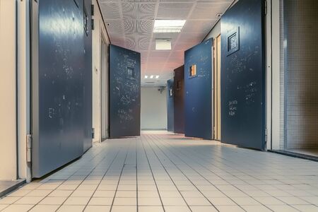 AMSTERDAM/NETHERLANDS-FEBRUARY 24: An empty corridor of a prison with tiles on the floor and open steel cell doors on which texts are scratched The cells are emptyの写真素材