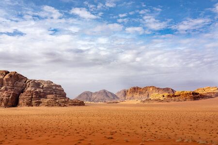 Red sand and rocks in the Wadi Rum desert in Jordan under a cloudy sky.の写真素材