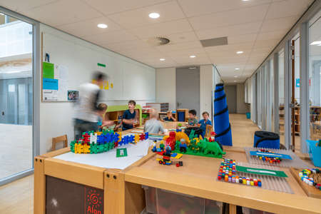 ARNHEM / NETHERLANDS - AUGUST 28 2020: Children in kindergarten play with toys. Other toys stored in cupboards, boxes and crates.のeditorial素材