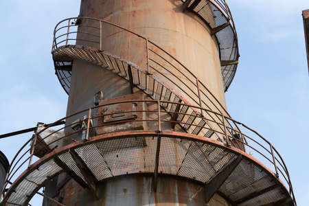 The remains of an old factory. The round steel chimney and the steel construction of the building are clearly visibleの写真素材