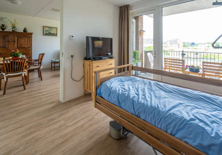 BREDA / NETHERLANDS - JUNE 22, 2021: A bed room in a care apartment with blue sheets and clothes hanging from the closetのeditorial素材