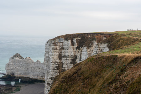 Characteristic coastline of Normandy, France with high cliffs and rocks under a gray skyの写真素材