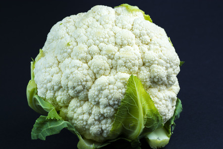 whole, fresh, ripe cauliflower on the black backgroundの写真素材