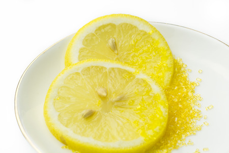 closeup two slices of fresh lemon with yellow sugar on the white plateの写真素材