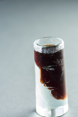 Three faces unusual shot glass with red wine.の写真素材