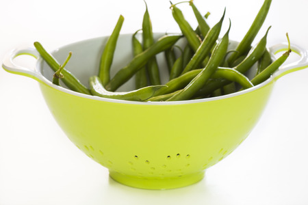 Closeup bunch of french, ripe, raw beans in a green bowl on the white background.の写真素材