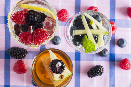Closeup of glasses of assorted berries and fruits infused water.