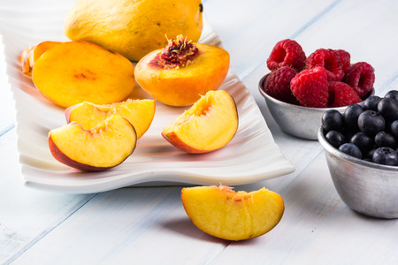 Close up of fresh cut peach slices and berries.の写真素材