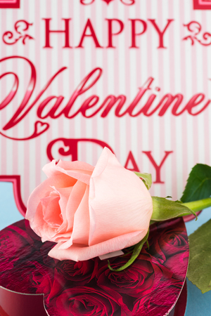 Close up of cut rose and heart shaped candy box on a blue background.の写真素材