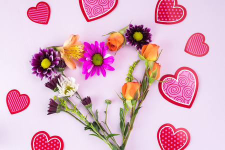 Close up of heart shaped flower arrangement on a pink wooden background.の写真素材