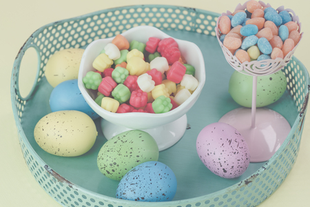 Close up of metal tray with easter colorful eggs and candies on  pastel background.