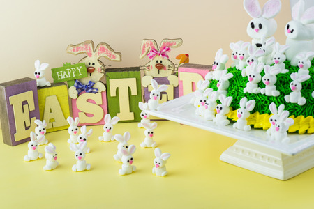 Close up of marshmallow bunnies and Easter bunny cake on cake platter on pastel background.